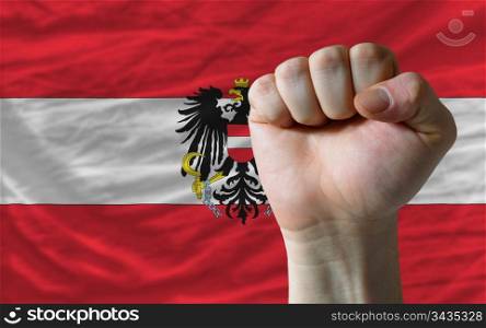 complete national flag of austria covers whole frame, waved, crunched and very natural looking. In front plan is clenched fist symbolizing determination