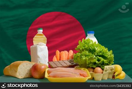 complete national flag of bangladesh covers whole frame, waved, crunched and very natural looking. In front plan are fundamental food ingredients for consumers, symbolizing consumerism an human needs