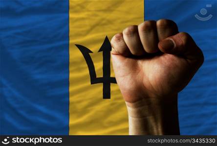 complete national flag of barbados covers whole frame, waved, crunched and very natural looking. In front plan is clenched fist symbolizing determination