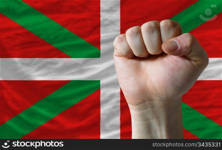 complete national flag of basque covers whole frame, waved, crunched and very natural looking. In front plan is clenched fist symbolizing determination