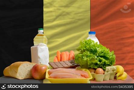 complete national flag of belgium covers whole frame, waved, crunched and very natural looking. In front plan are fundamental food ingredients for consumers, symbolizing consumerism an human needs