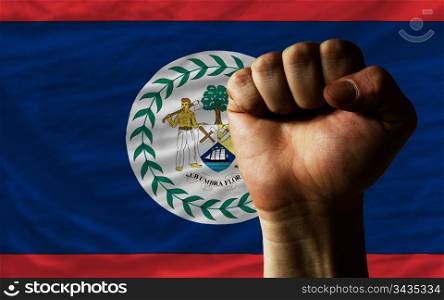 complete national flag of belize covers whole frame, waved, crunched and very natural looking. In front plan is clenched fist symbolizing determination