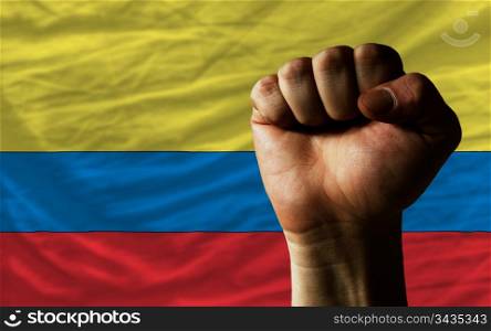 complete national flag of colombia covers whole frame, waved, crunched and very natural looking. In front plan is clenched fist symbolizing determination
