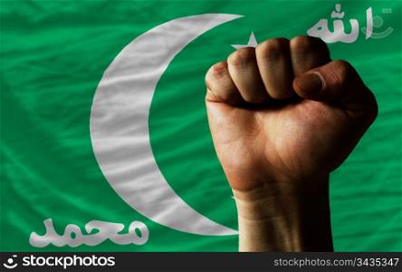 complete national flag of comoros covers whole frame, waved, crunched and very natural looking. In front plan is clenched fist symbolizing determination