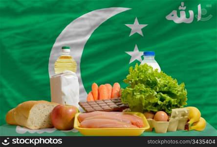 complete national flag of comoros covers whole frame, waved, crunched and very natural looking. In front plan are fundamental food ingredients for consumers, symbolizing consumerism an human needs