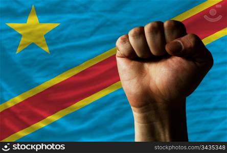 complete national flag of congo covers whole frame, waved, crunched and very natural looking. In front plan is clenched fist symbolizing determination