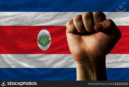 complete national flag of costarica covers whole frame, waved, crunched and very natural looking. In front plan is clenched fist symbolizing determination