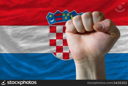 complete national flag of croatia covers whole frame, waved, crunched and very natural looking. In front plan is clenched fist symbolizing determination