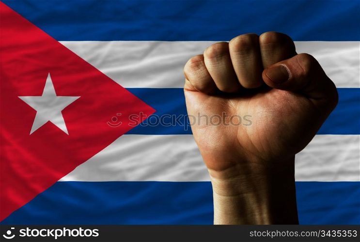 complete national flag of cuba covers whole frame, waved, crunched and very natural looking. In front plan is clenched fist symbolizing determination