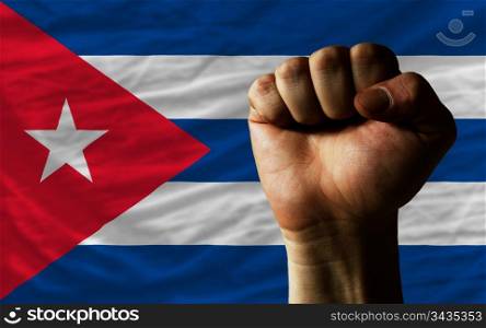 complete national flag of cuba covers whole frame, waved, crunched and very natural looking. In front plan is clenched fist symbolizing determination