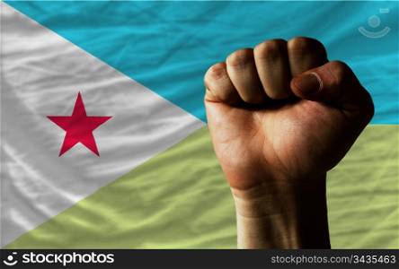 complete national flag of djibouti covers whole frame, waved, crunched and very natural looking. In front plan is clenched fist symbolizing determination