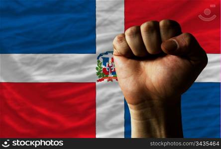 complete national flag of dominican covers whole frame, waved, crunched and very natural looking. In front plan is clenched fist symbolizing determination