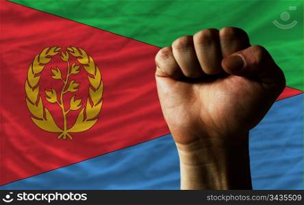 complete national flag of eritrea covers whole frame, waved, crunched and very natural looking. In front plan is clenched fist symbolizing determination