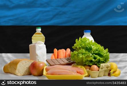 complete national flag of estonia covers whole frame, waved, crunched and very natural looking. In front plan are fundamental food ingredients for consumers, symbolizing consumerism an human needs