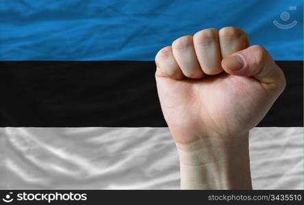 complete national flag of estonia covers whole frame, waved, crunched and very natural looking. In front plan is clenched fist symbolizing determination