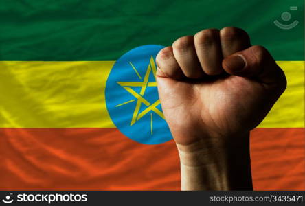 complete national flag of ethiopia covers whole frame, waved, crunched and very natural looking. In front plan is clenched fist symbolizing determination