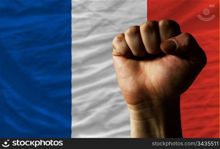 complete national flag of france covers whole frame, waved, crunched and very natural looking. In front plan is clenched fist symbolizing determination
