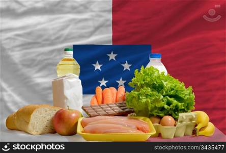 complete national flag of franceville covers whole frame, waved, crunched and very natural looking. In front plan are fundamental food ingredients for consumers, symbolizing consumerism an human needs
