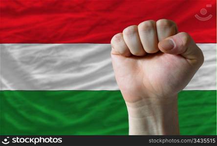 complete national flag of hungary covers whole frame, waved, crunched and very natural looking. In front plan is clenched fist symbolizing determination