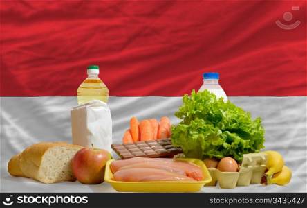 complete national flag of indonesia covers whole frame, waved, crunched and very natural looking. In front plan are fundamental food ingredients for consumers, symbolizing consumerism an human needs