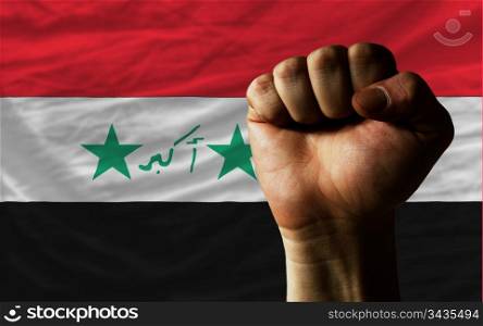 complete national flag of iraq covers whole frame, waved, crunched and very natural looking. In front plan is clenched fist symbolizing determination
