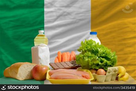 complete national flag of ireland covers whole frame, waved, crunched and very natural looking. In front plan are fundamental food ingredients for consumers, symbolizing consumerism an human needs
