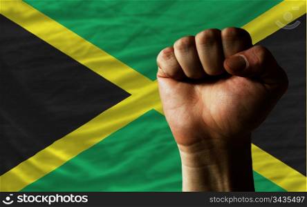 complete national flag of jamaica covers whole frame, waved, crunched and very natural looking. In front plan is clenched fist symbolizing determination