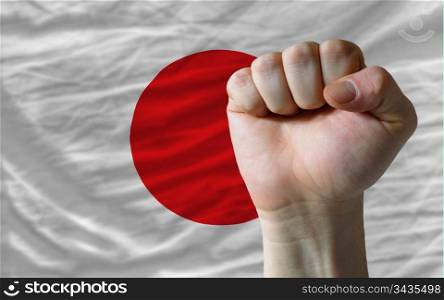 complete national flag of japan covers whole frame, waved, crunched and very natural looking. In front plan is clenched fist symbolizing determination