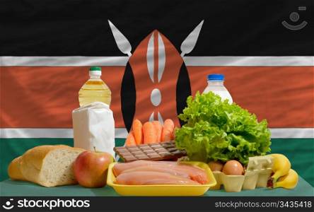 complete national flag of kenya covers whole frame, waved, crunched and very natural looking. In front plan are fundamental food ingredients for consumers, symbolizing consumerism an human needs