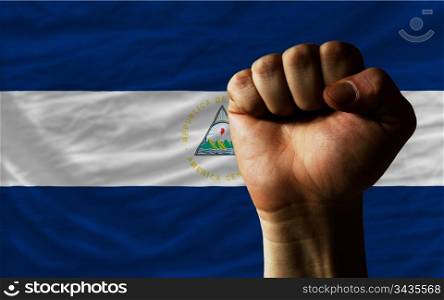 complete national flag of nicaragua covers whole frame, waved, crunched and very natural looking. In front plan is clenched fist symbolizing determination