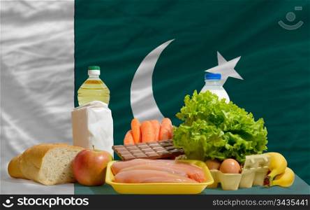 complete national flag of pakistan covers whole frame, waved, crunched and very natural looking. In front plan are fundamental food ingredients for consumers, symbolizing consumerism an human needs