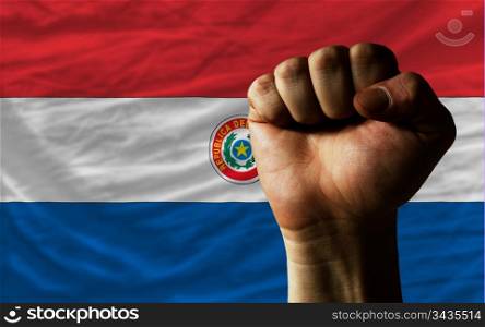 complete national flag of paraguay covers whole frame, waved, crunched and very natural looking. In front plan is clenched fist symbolizing determination