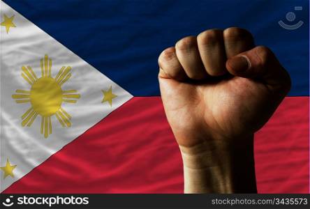 complete national flag of philippines covers whole frame, waved, crunched and very natural looking. In front plan is clenched fist symbolizing determination