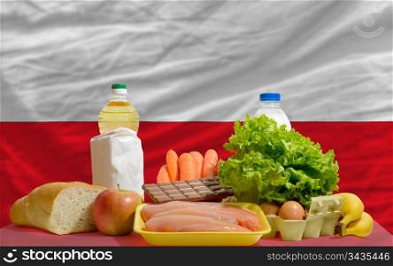 complete national flag of poland covers whole frame, waved, crunched and very natural looking. In front plan are fundamental food ingredients for consumers, symbolizing consumerism an human needs