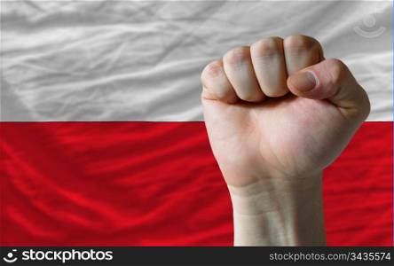 complete national flag of poland covers whole frame, waved, crunched and very natural looking. In front plan is clenched fist symbolizing determination