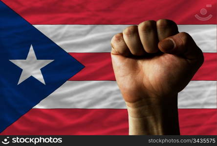 complete national flag of puertorico covers whole frame, waved, crunched and very natural looking. In front plan is clenched fist symbolizing determination