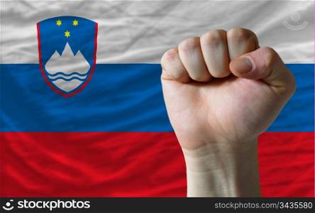 complete national flag of slovenia covers whole frame, waved, crunched and very natural looking. In front plan is clenched fist symbolizing determination