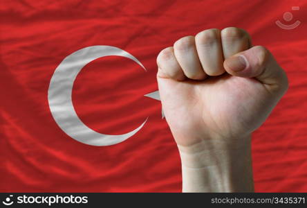 complete national flag of turkey covers whole frame, waved, crunched and very natural looking. In front plan is clenched fist symbolizing determination