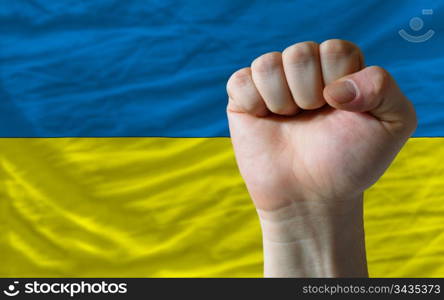 complete national flag of ukraine covers whole frame, waved, crunched and very natural looking. In front plan is clenched fist symbolizing determination