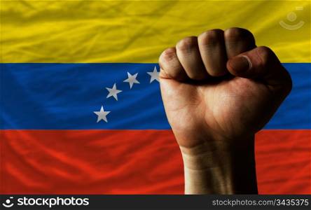 complete national flag of venezuela covers whole frame, waved, crunched and very natural looking. In front plan is clenched fist symbolizing determination