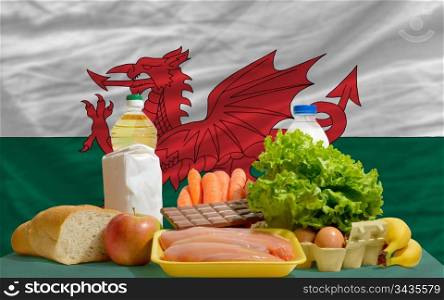 complete national flag of wales covers whole frame, waved, crunched and very natural looking. In front plan are fundamental food ingredients for consumers, symbolizing consumerism an human needs