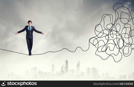 Complicated case. Businessman walking on twisted rope high in sky