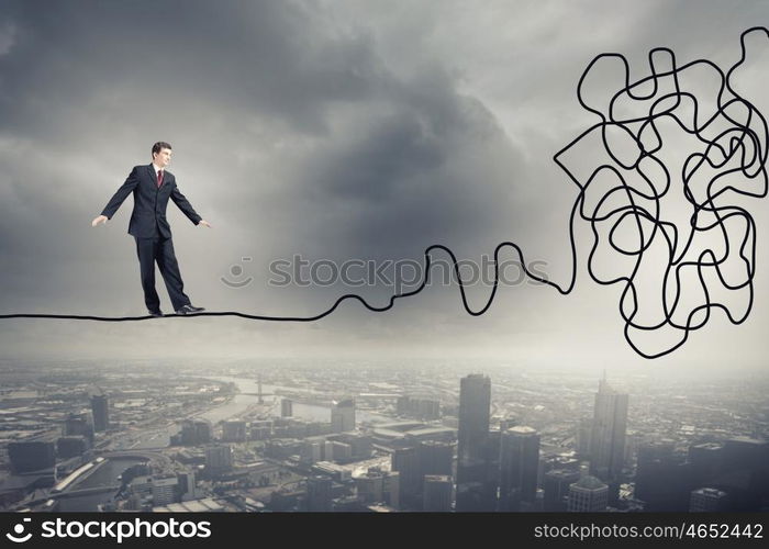 Complicated case. Businessman walking on twisted rope high in sky