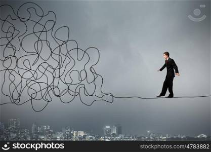 Complicated case. Businessman walking on twisted rope high in sky