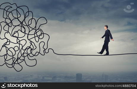 Complicated case. Businessman walking on twisted rope high in sky