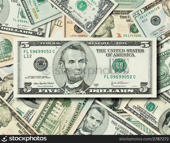 Composite shot of different American Dollar bills piled together with Lincoln&acute;s 5 dollar bill in front.