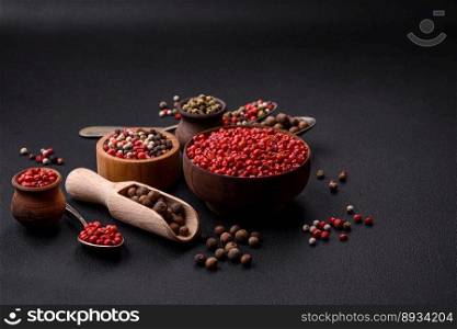 Composition, concept, consisting of several types of different colors of allsπce in bowls and spoons on a dark concrete background