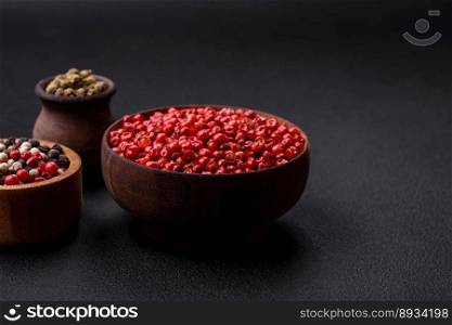 Composition, concept, consisting of several types of different colors of allspice in bowls and spoons on a dark concrete background