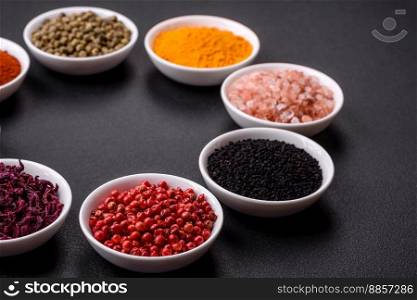 Composition consisting of a variation of several types of spices in white ceramic bowls on a textured concrete background