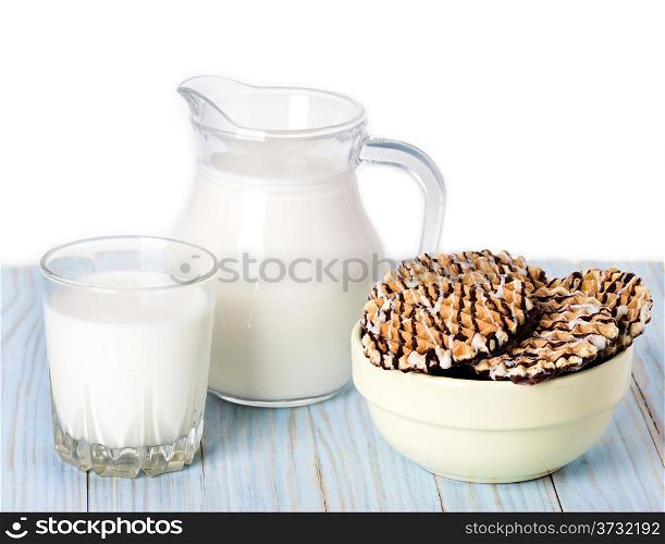 Composition milk in a jug, a glass and cookies on blue wooden background